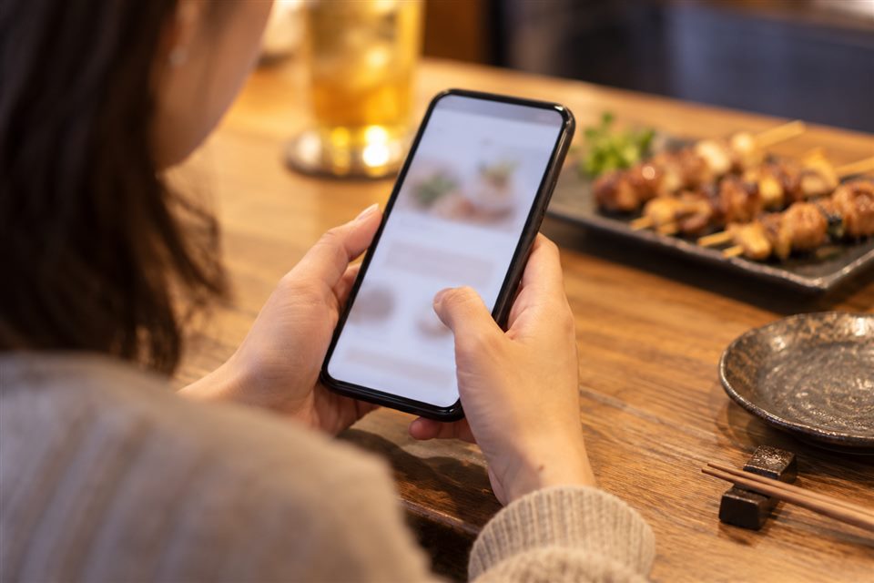食卓でスマートフォンの画面を確認する手元
